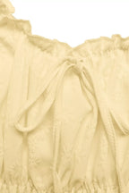 Light yellow top with ruffled details on a white background