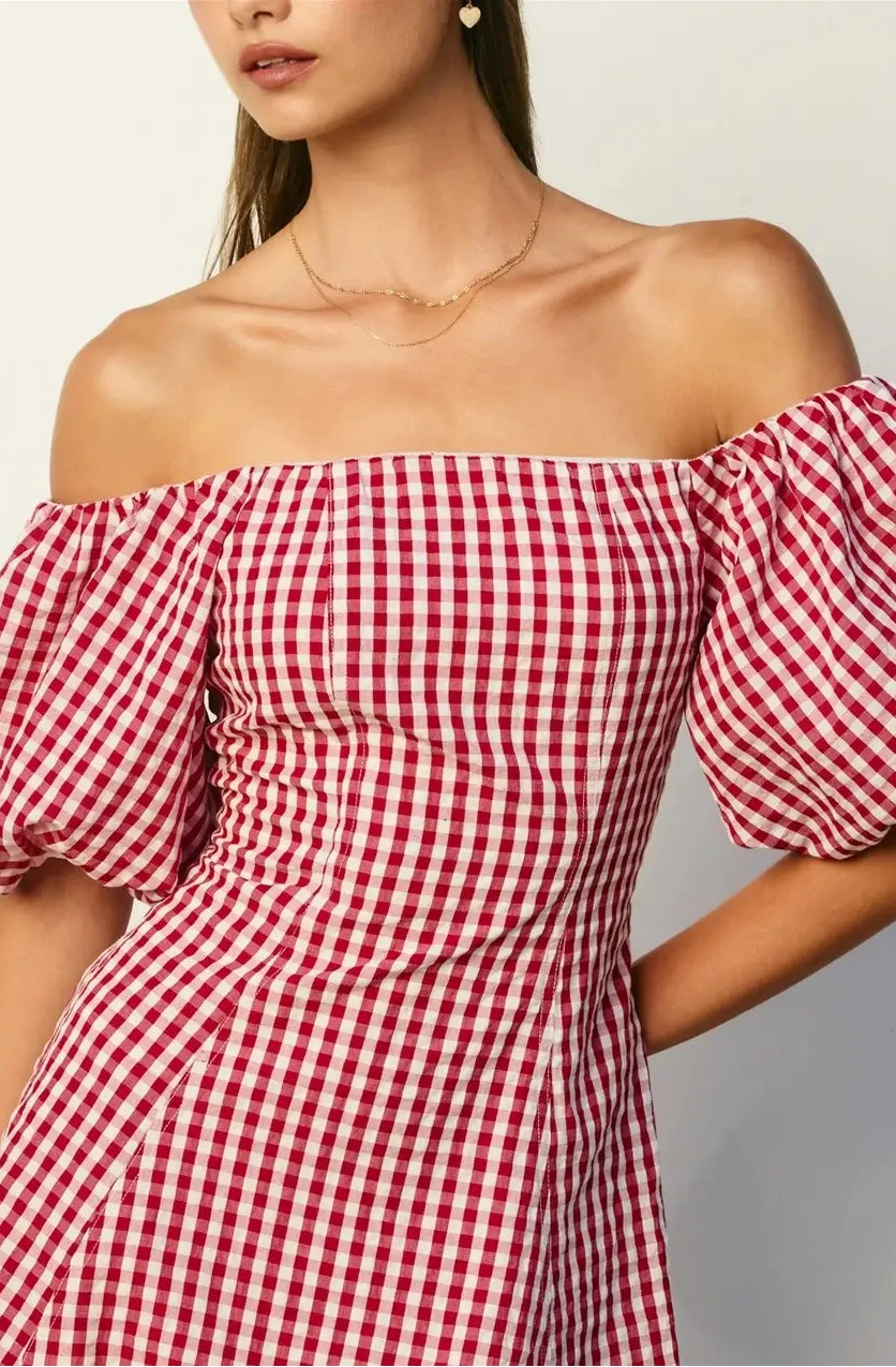 Red and white checkered off-shoulder dress worn by a model on a plain background