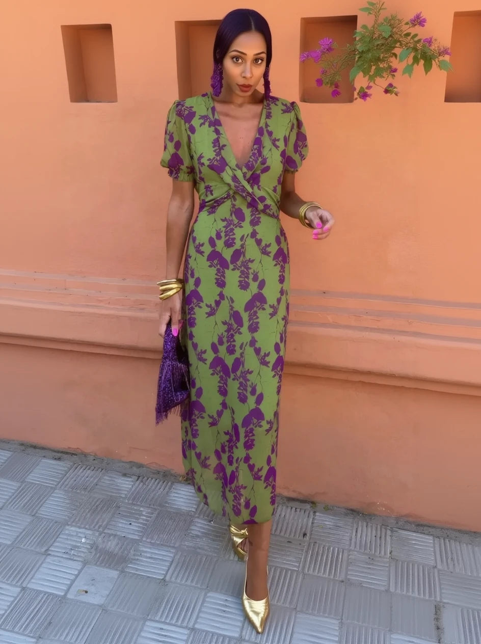 Woman wearing a green and purple floral dress against an orange wall.