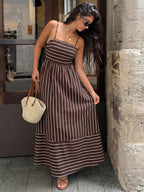 Woman in a brown and white striped dress standing against a stone wall.