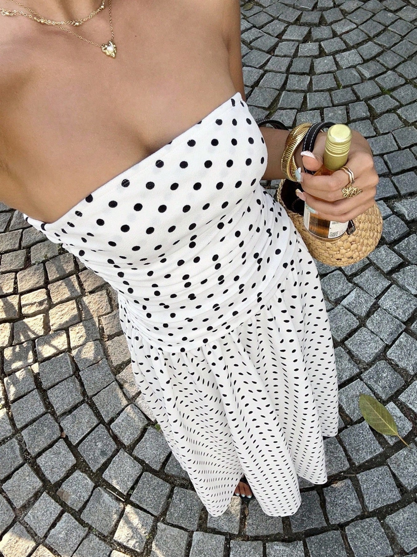 Woman wearing a strapless polka dot dress holding a bottle of wine posing