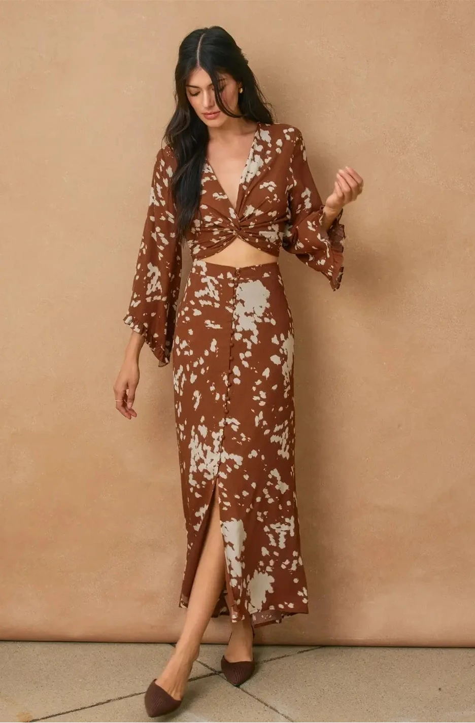Woman wearing a brown floral dress against a beige wall
