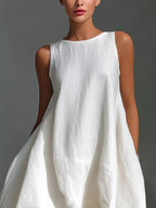 Woman wearing a white sleeveless dress against a gray background