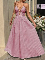 Woman wearing a pink and white striped dress standing outdoors with flowers in the background