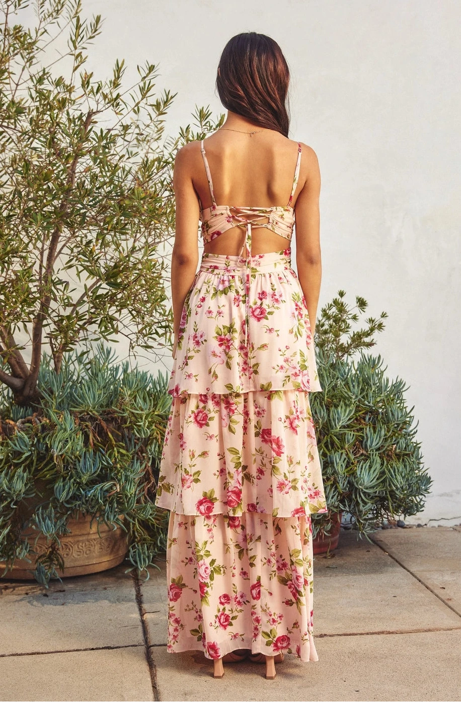 Woman wearing a floral dress standing outdoors with plants in the background