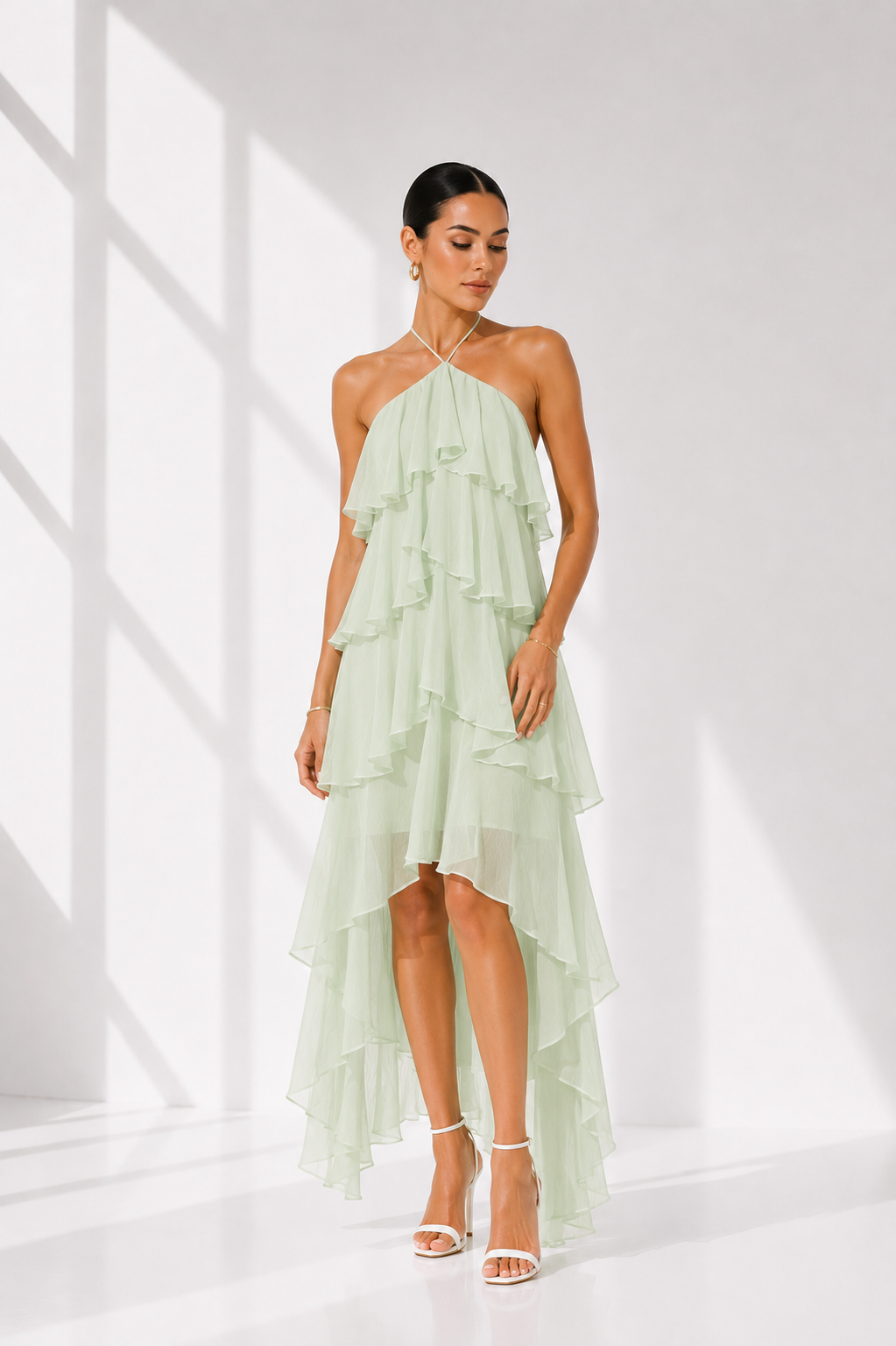 Woman wearing a light green ruffled dress against a white background