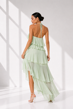 Woman wearing a light green dress with a backless design in a bright room.