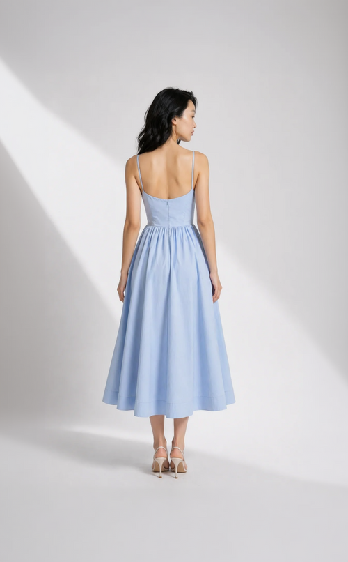 Woman wearing a light blue dress with thin straps on a white background