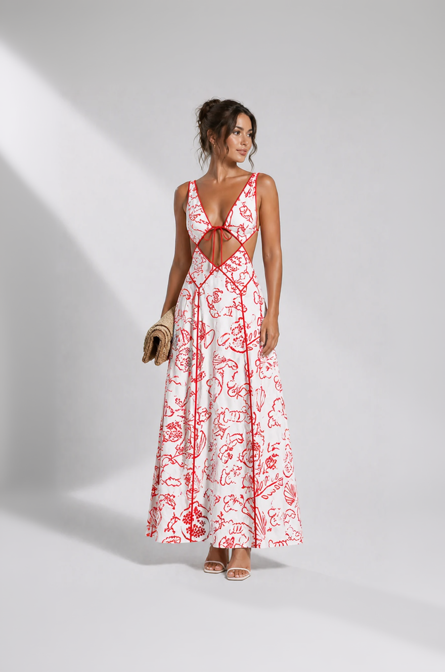 Woman wearing a white dress with red floral patterns and cut-out design on a plain background
