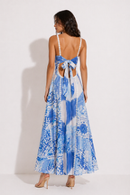 Woman wearing a blue and white floral dress with cut-out back on a white background