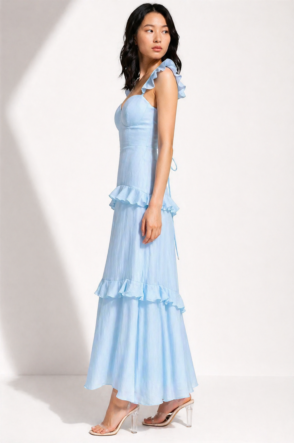 Woman wearing a light blue dress with ruffled layers on a white background