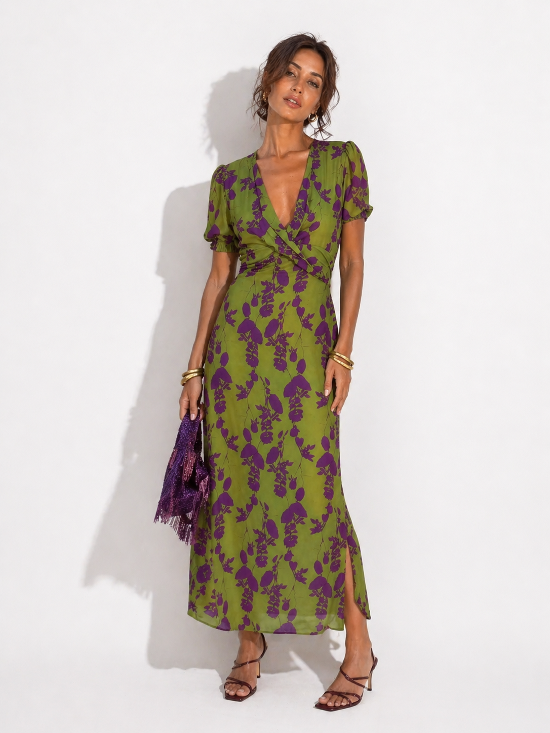 Woman wearing a green and purple floral dress against a white background