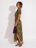 Woman wearing a green and purple floral dress against a white background