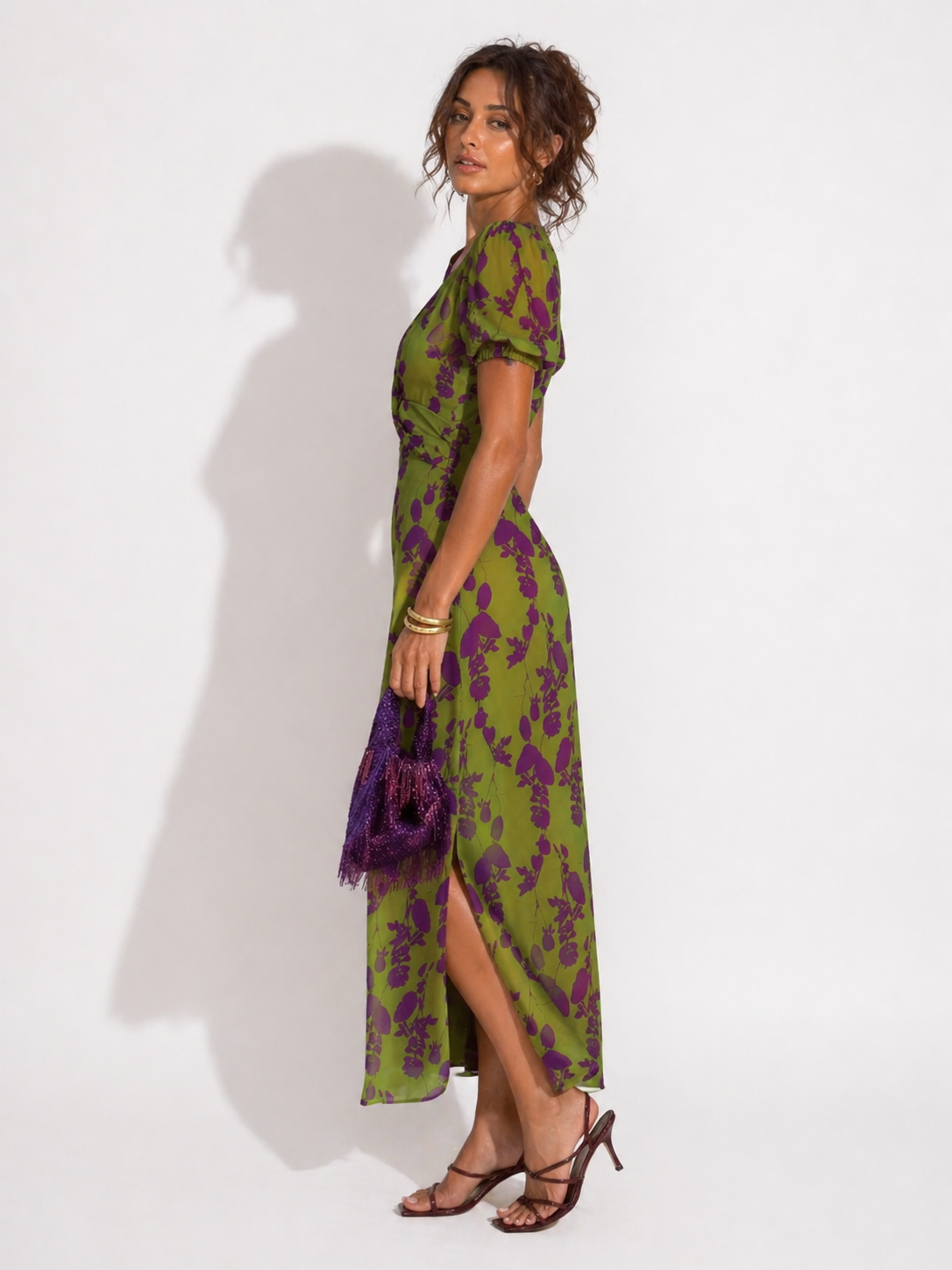 Woman wearing a green and purple floral dress against a white background