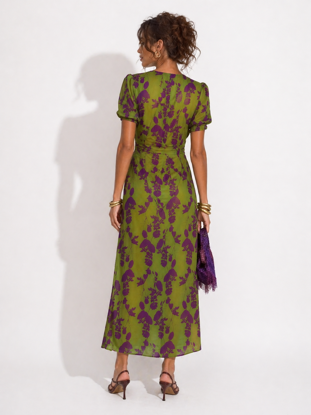 Woman wearing a green and purple floral dress against a white background