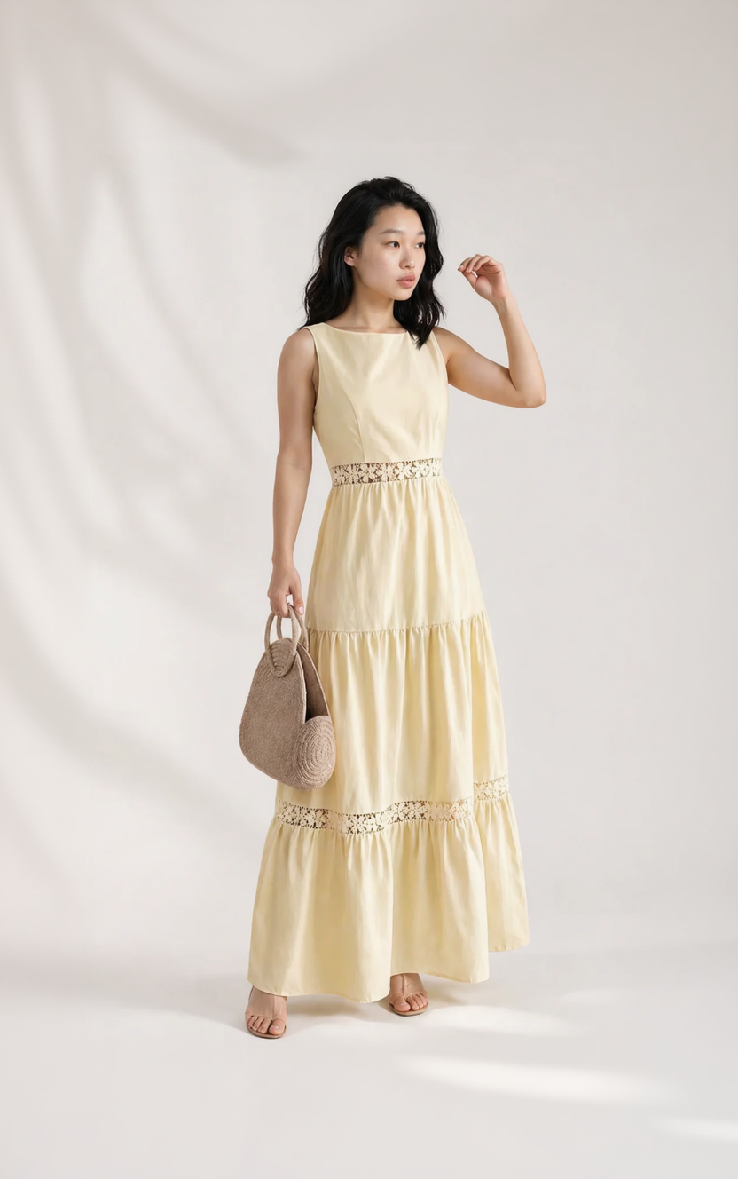 Woman wearing a light yellow dress with lace details, holding a beige handbag on a white background