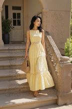 Woman in a yellow dress standing on stone steps outdoors