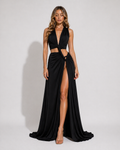 Woman wearing a black evening gown with a high slit on a plain background