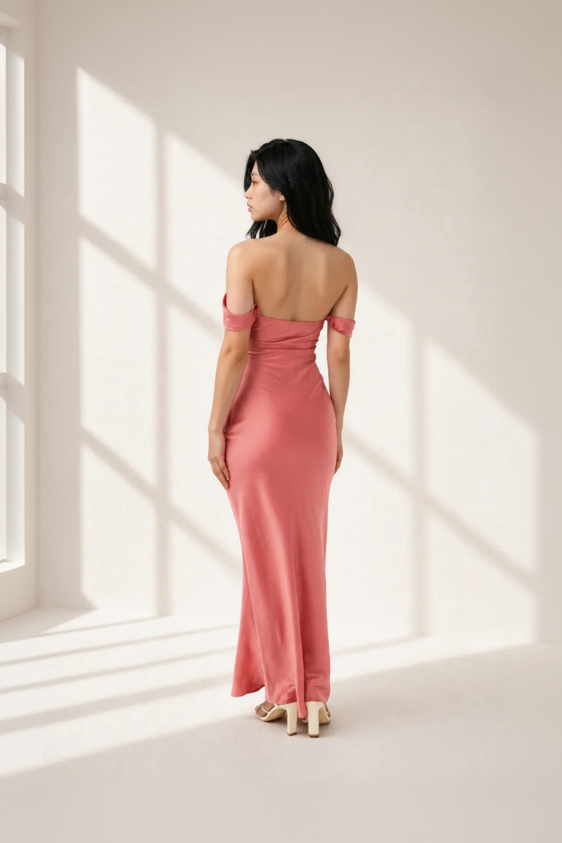 Woman wearing a pink evening gown standing in a softly lit room.