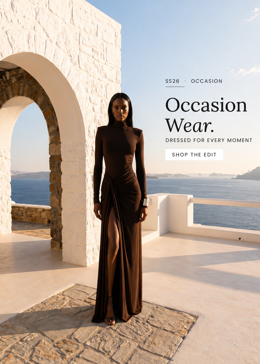 Woman in a long brown dress standing in front of stone arches with a scenic background.