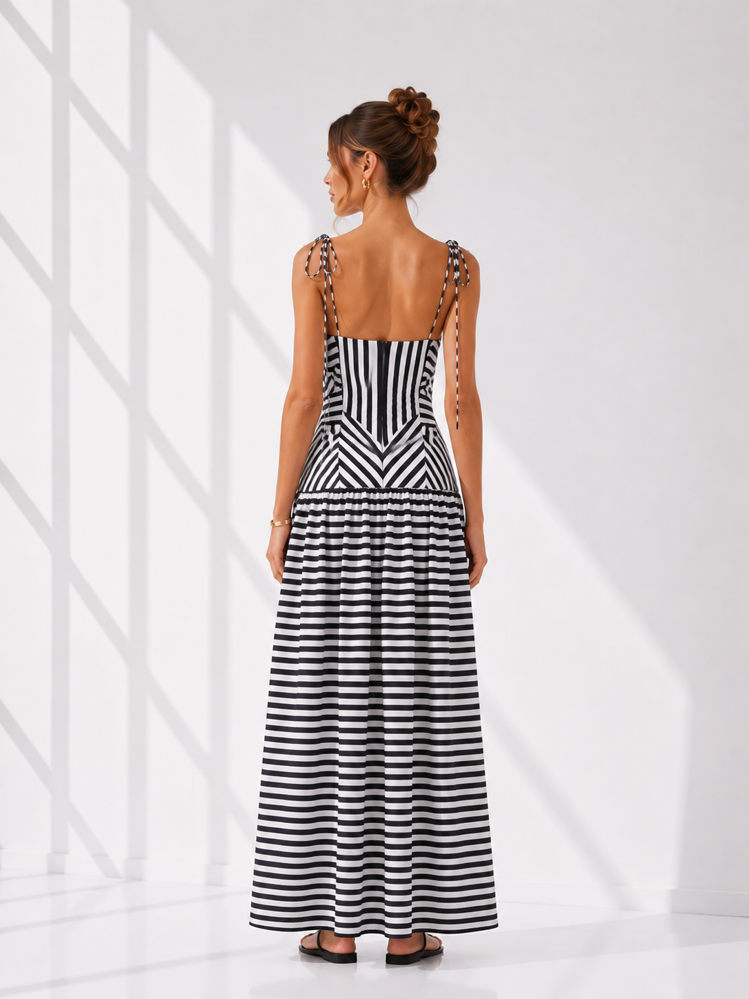 Woman wearing a black and white striped dress with a geometric pattern on a white background