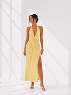 Woman wearing a yellow halter neck dress with a slit on a white background