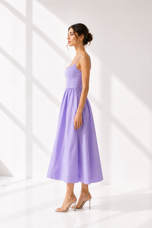 Woman wearing a purple dress standing against a white background