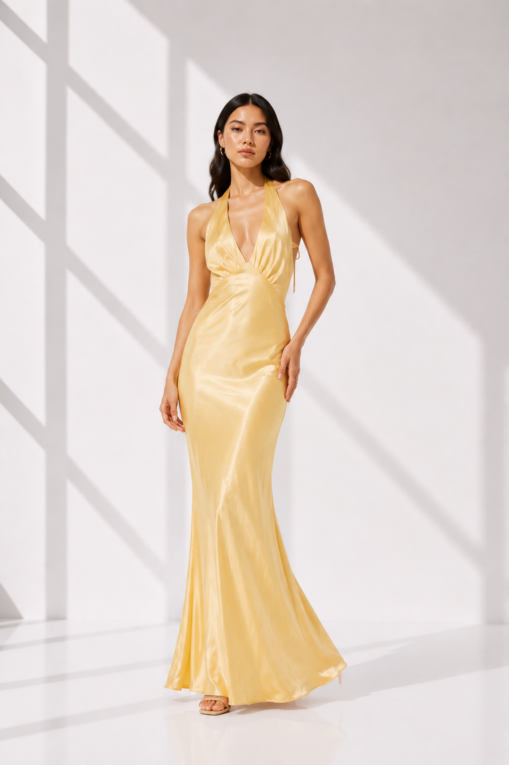 Woman wearing a yellow evening gown in a bright room with white walls.