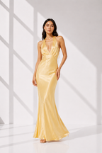 Woman wearing a yellow evening gown in a bright room with white walls.
