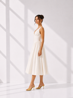 Woman wearing a white dress standing against a white background