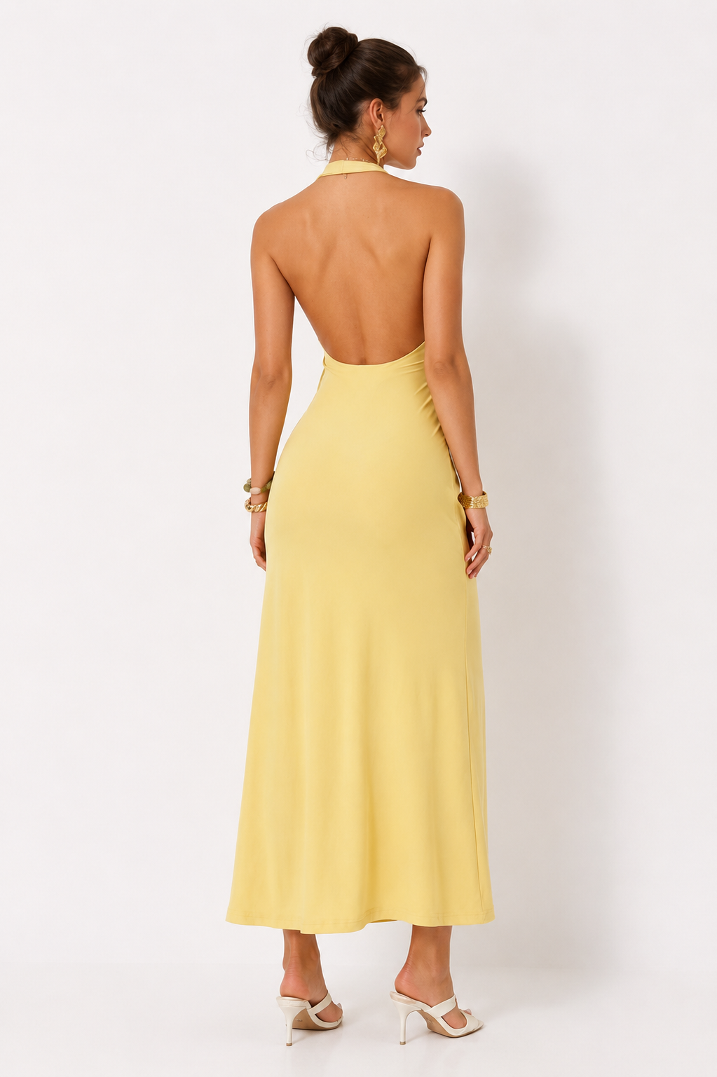 Woman wearing a yellow halter neck dress against a white background