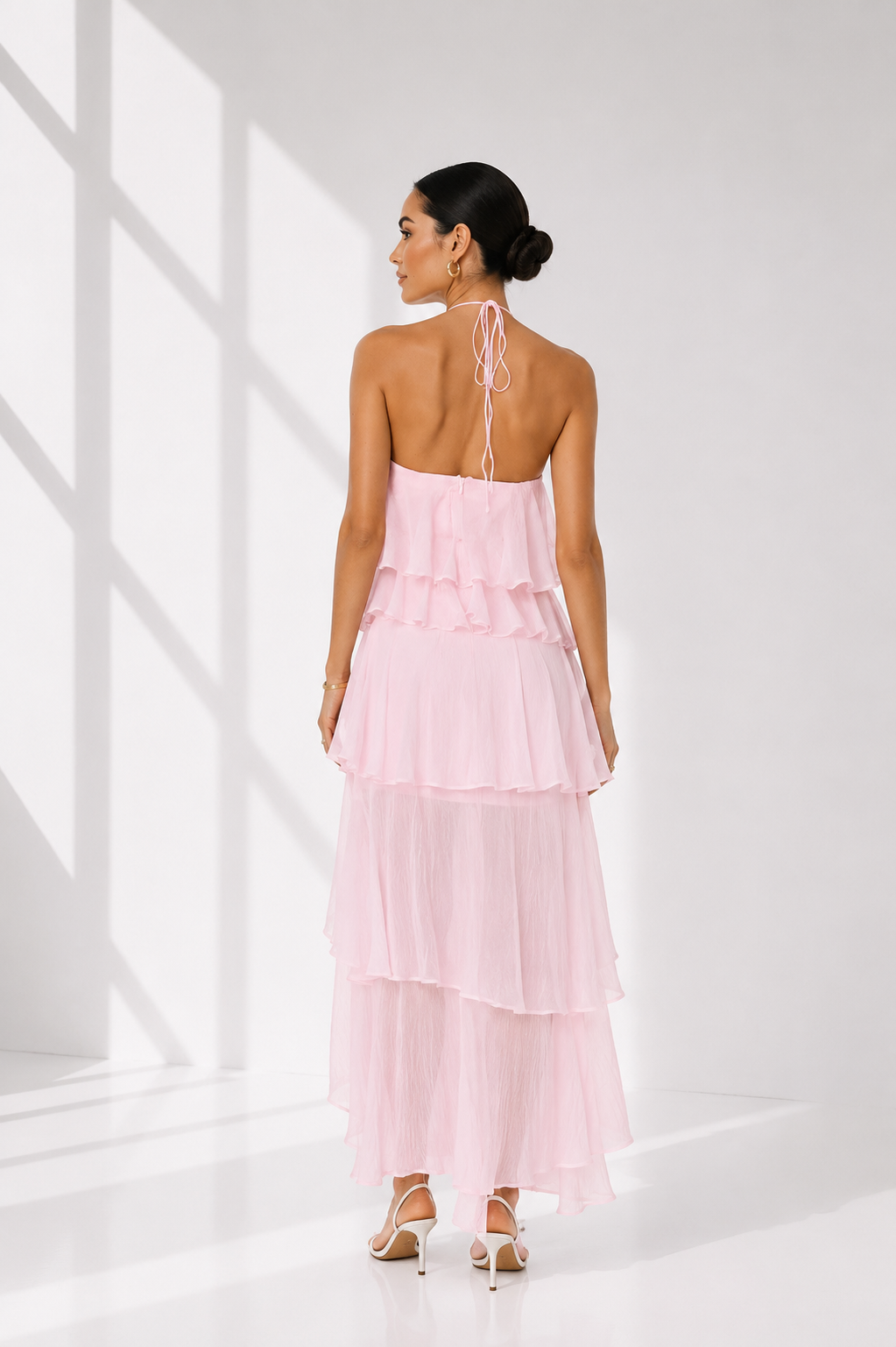 Woman wearing a pink halter neck dress in a minimal white setting