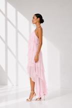 Woman wearing a pink dress standing in a bright, minimalistic room.