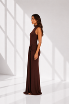 Woman wearing a brown evening gown in a white room with light patterns on the floor.