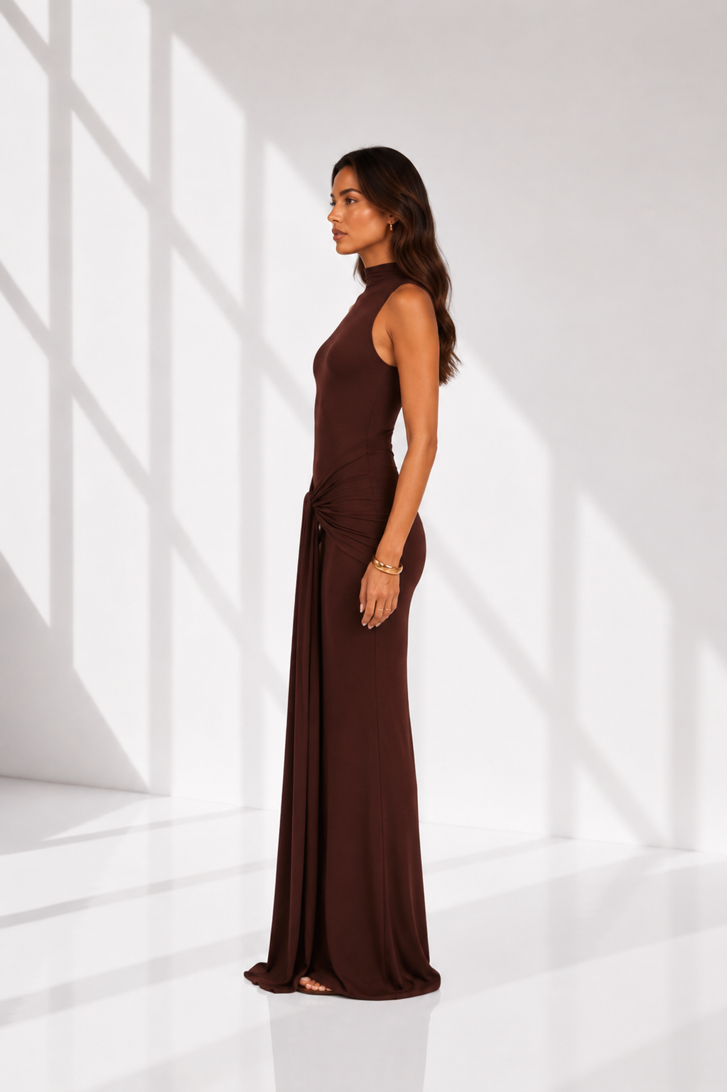 Woman wearing a brown evening gown in a white room with light patterns on the floor.