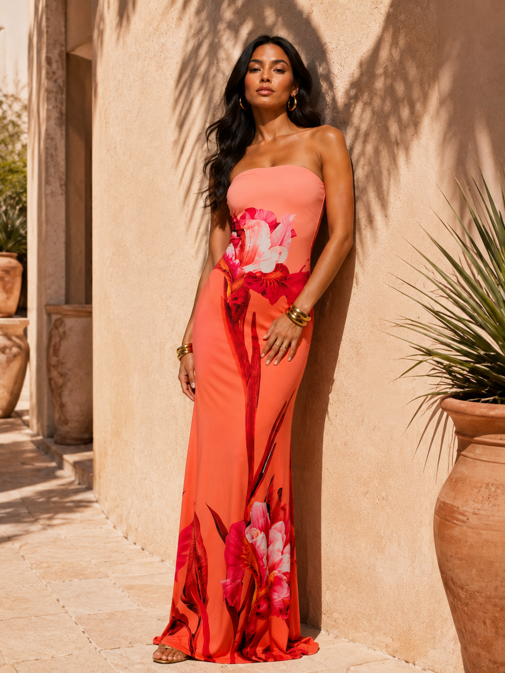 Woman in a strapless floral dress standing against a beige wall with potted plants.