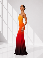 Woman wearing a strapless, gradient dress with orange to red color scheme on a white background