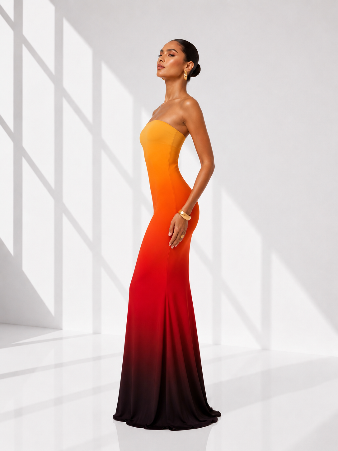 Woman wearing a strapless, gradient dress with orange to red color scheme on a white background
