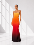 Woman wearing a strapless, gradient dress with orange to red color scheme on a white background