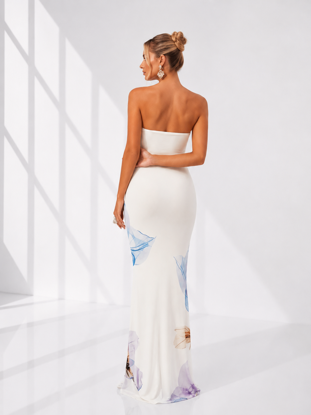 Woman wearing a strapless white gown with sheer sides in a bright room.