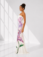 Woman wearing a strapless floral gown against a white background