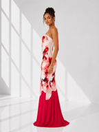Woman wearing a strapless dress with red and white floral pattern in a bright room.