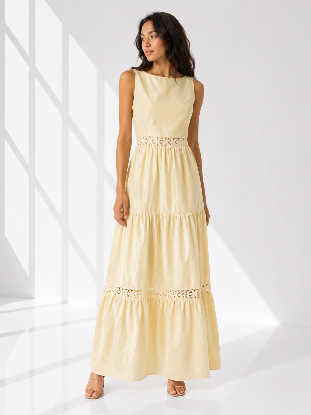Woman wearing a light yellow dress with lace details in a bright room.