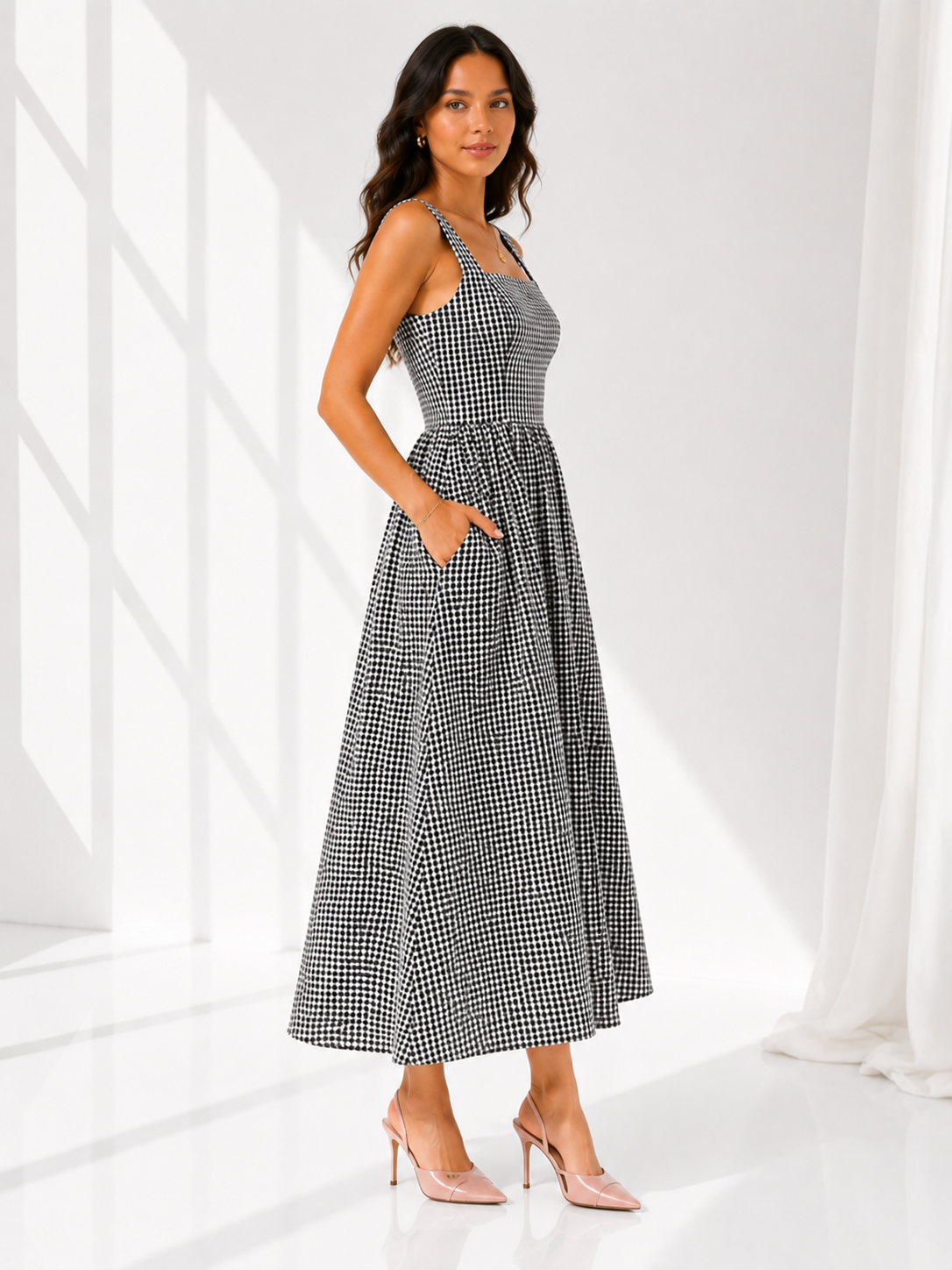 Woman wearing a black and white checkered dress in a bright room.
