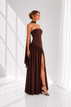 Woman wearing a brown strapless dress with a slit in a minimalistic setting