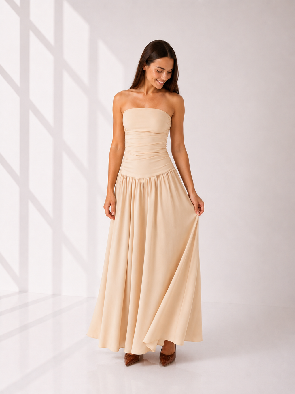 Woman wearing a beige strapless dress against a white background