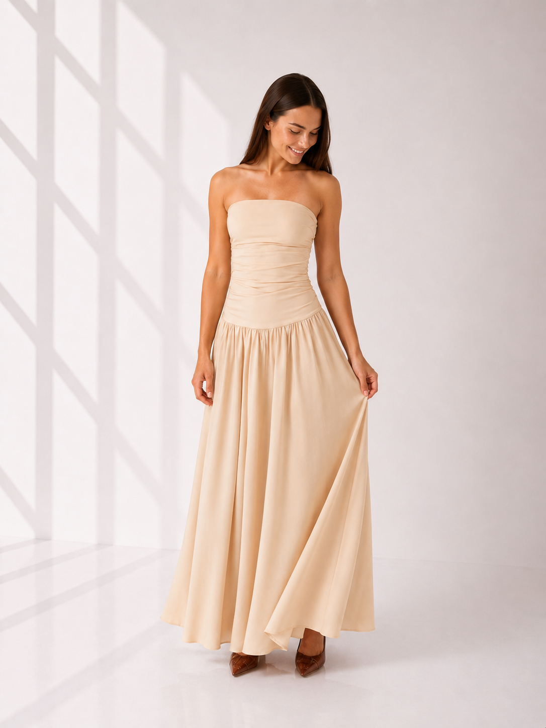 Woman wearing a beige strapless dress against a white background