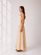 Woman wearing a beige strapless gown against a white background