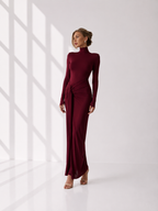 Woman wearing a burgundy dress with long sleeves and a high neckline.