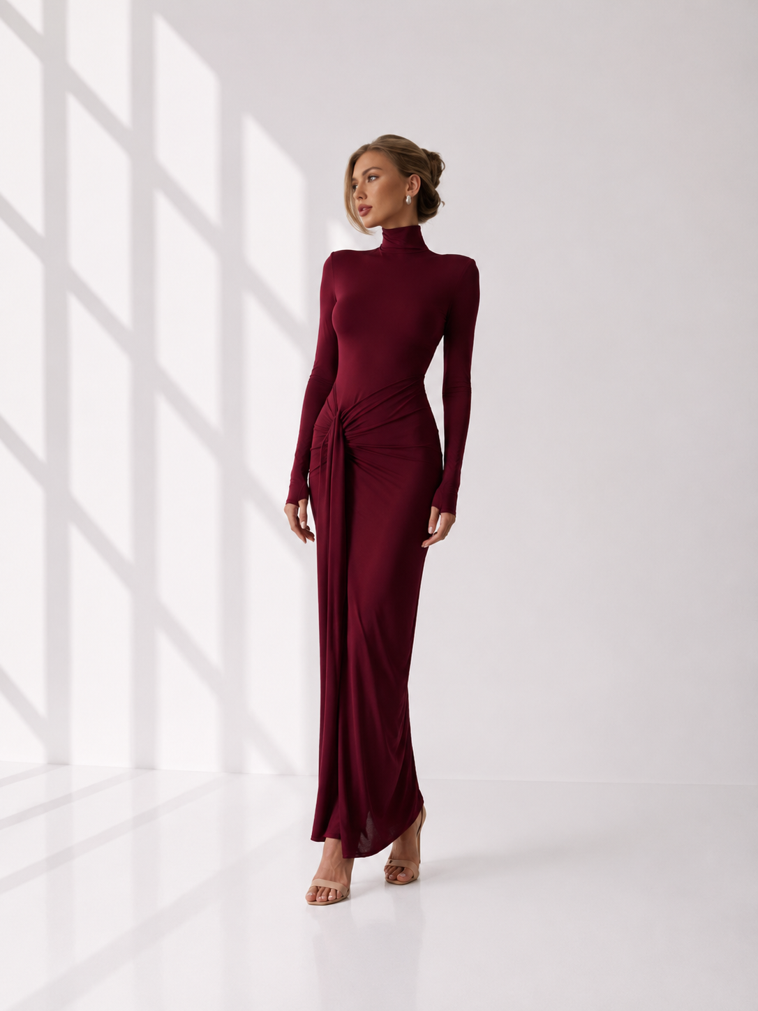 Woman wearing a burgundy dress with long sleeves and a high neckline.